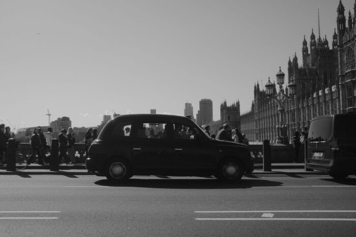Black London taxi beside pedestrians and Parliament buildings