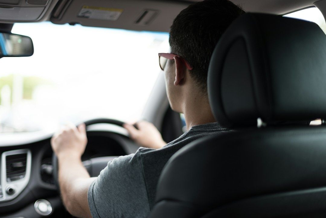 Driver seated at the wheel, viewed from behind inside a car