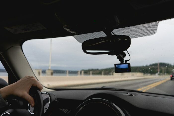 Dashcam mounted behind a car’s rear-view mirror on a rainy road